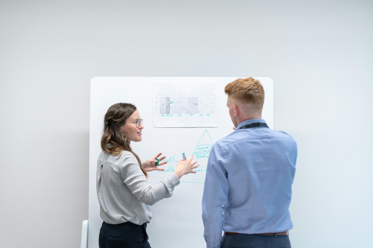 Zwei Personen besprechen eine Skizze an einem Whiteboard